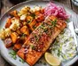Oven-roasted salmon with browned vegetables and lemon on a baking tray