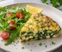 Sliced spinach and feta frittata beside rocket, cherry tomatoes and curly parsley