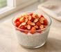 Chia-yogurt pudding in a glass topped with chopped strawberries and toasted sliced almonds